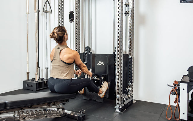 An athlete performing a low cable row on the Wall-Mounted Ares™ 2.0 while seated on a REP BlackWing™ bench