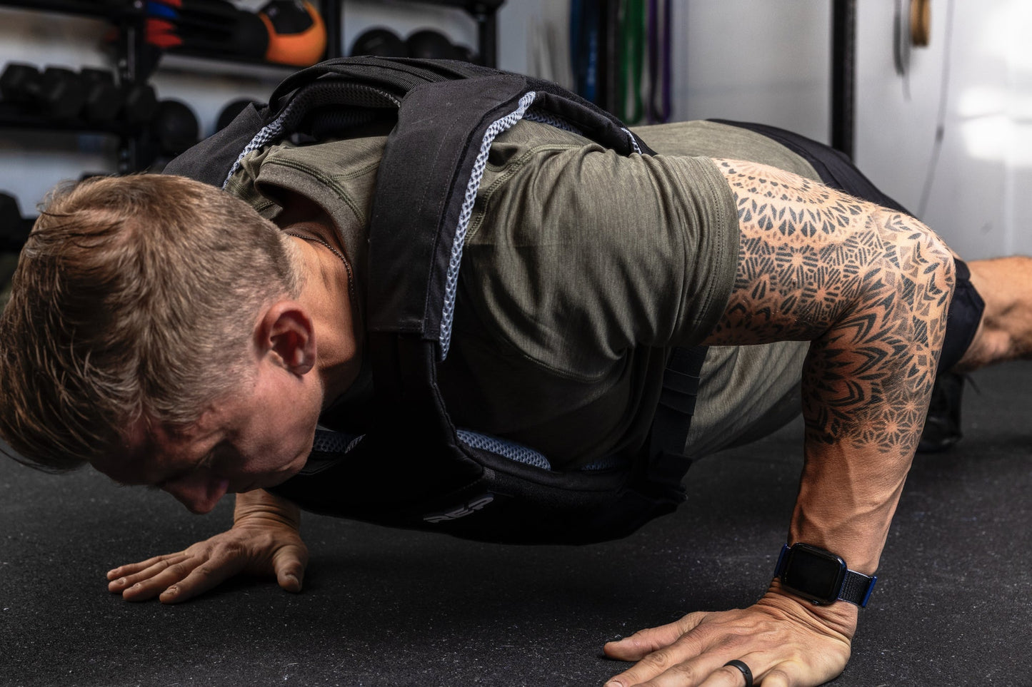 Person performing push-ups with a weight vest  and soft weight vest plates in a gym setting